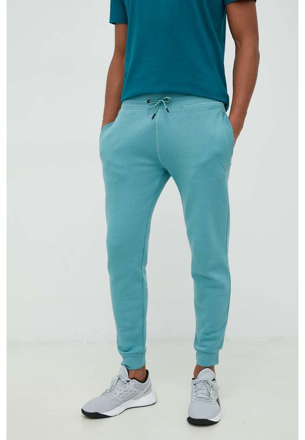 Guess spodnie dresowe kolor niebieski melanżowe. Kolor: niebieski. Materiał: dresówka. Wzór: melanż