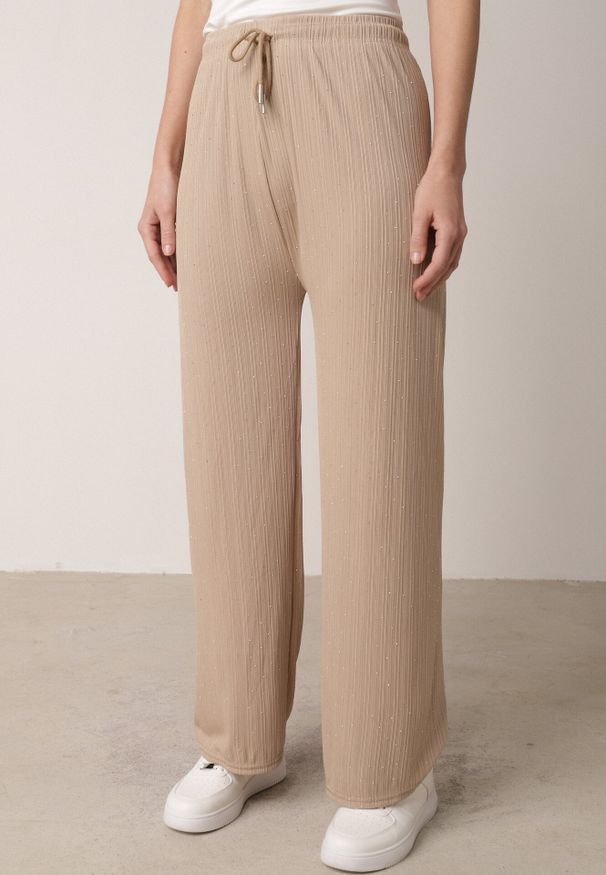 Born2be - Beżowe Szerokie Spodnie z Bawełną Zdobione Cyrkoniami Azilene. Okazja: na co dzień. Stan: podwyższony. Kolor: beżowy. Materiał: bawełna. Wzór: aplikacja. Styl: casual, klasyczny