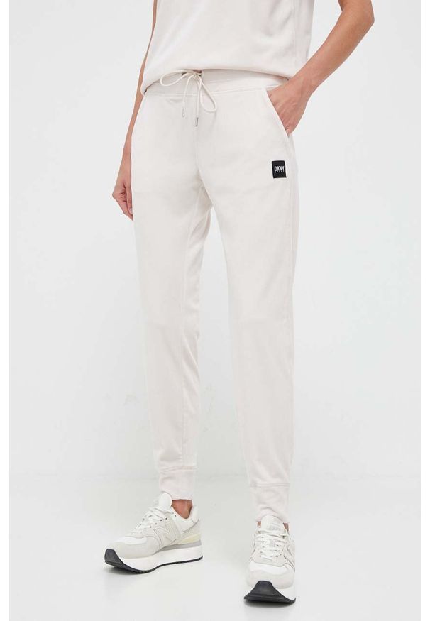 DKNY - Dkny spodnie dresowe kolor beżowy gładkie. Kolor: beżowy. Materiał: dresówka. Wzór: gładki