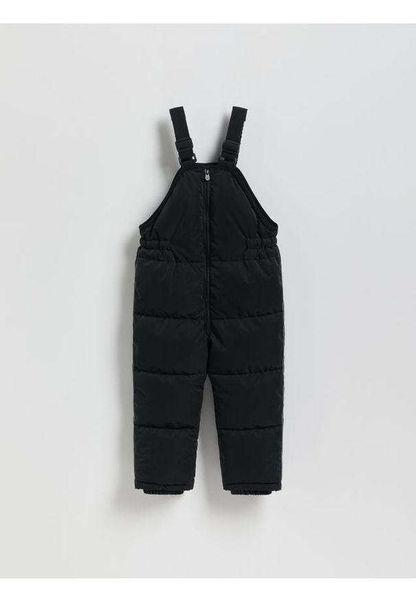 Reserved - Gumowane spodnie na szelkach - czarny. Kolor: czarny. Materiał: materiał