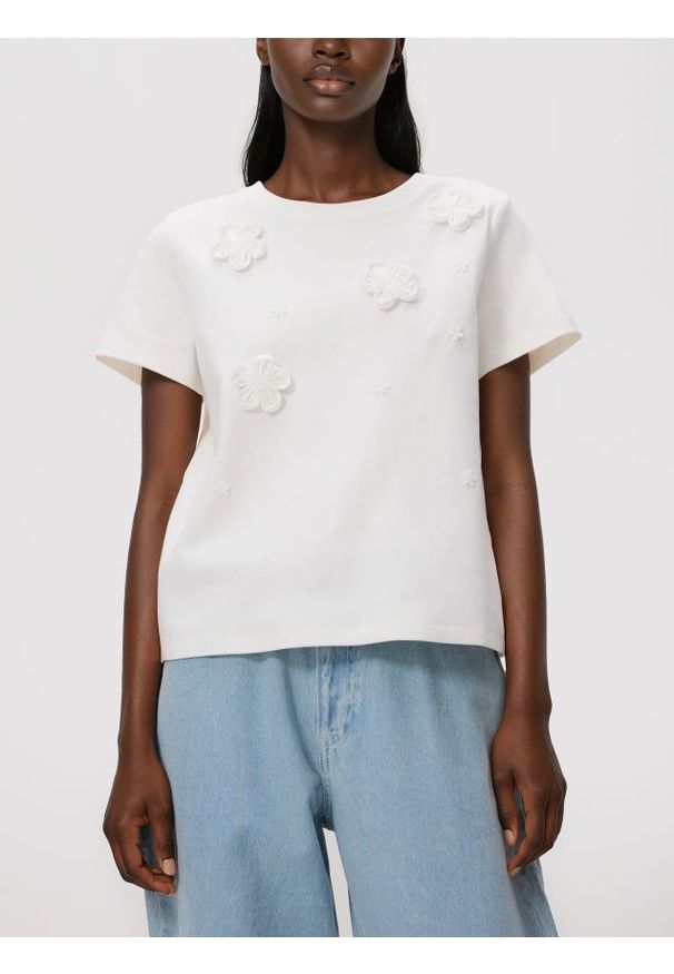 Reserved - T-shirt z kwiatową aplikacją - złamana biel. Materiał: dzianina, bawełna. Wzór: aplikacja, kwiaty