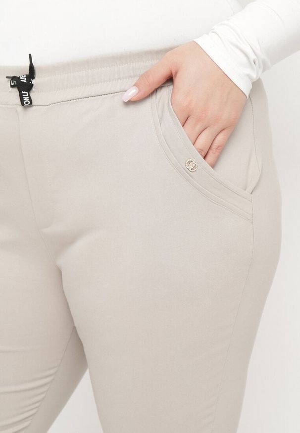 Born2be - Beżowe Spodnie 3/4 z Gumką w Pasie i Troczkiem Ozdobione Cyrkoniami Nazairia. Okazja: na co dzień. Kolor: beżowy. Wzór: aplikacja. Styl: casual