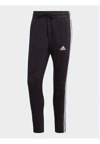 Adidas - adidas Spodnie dresowe Essentials Single Jersey Tapered Open Hem 3-Stripes Joggers IC0044 Czarny Regular Fit. Kolor: czarny. Materiał: bawełna