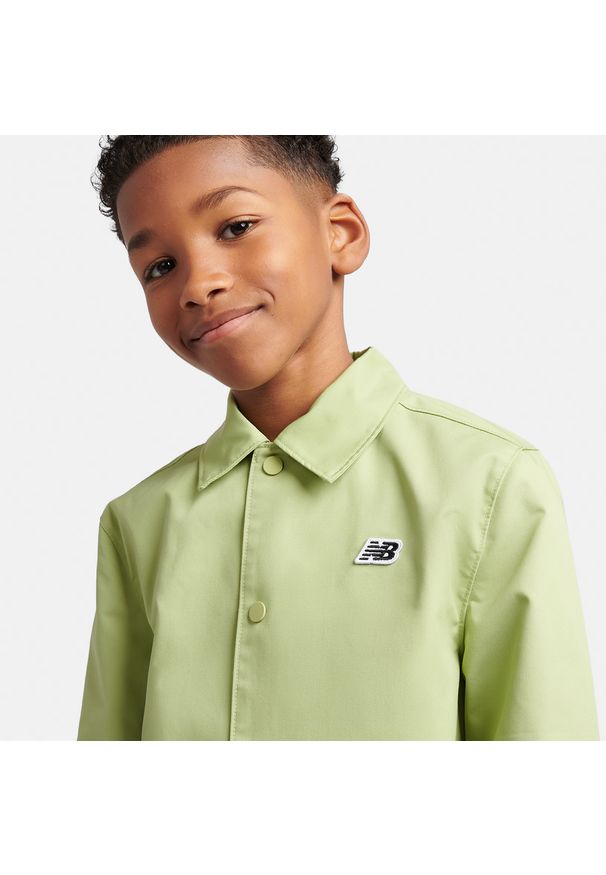 Kurtka dziecięca New Balance LAKB0140EEN – zielona. Kolor: zielony. Materiał: bawełna, poliester. Wzór: aplikacja, napisy. Styl: młodzieżowy