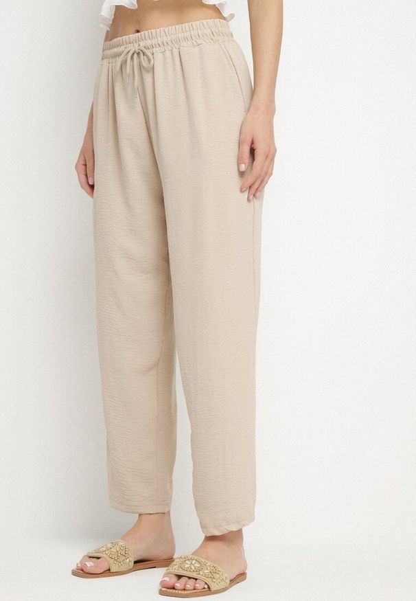 Born2be - Beżowe Spodnie Luźne z Kieszeniami i Gumką w Talii oraz Sznurkiem Enivia. Okazja: na co dzień. Kolor: beżowy. Styl: elegancki, casual