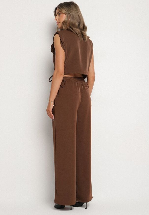 Born2be - Brązowy Komplet Kopertowa Bluzka z Kwiatową Broszką i Szerokie Spodnie Reavilia. Kolor: brązowy. Wzór: kwiaty