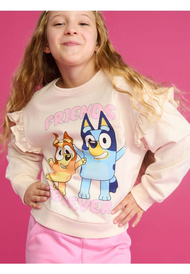 Sinsay - Bluza z nadrukiem Bluey - kremowy. Typ kołnierza: kołnierz z falbankami. Kolor: kremowy. Długość rękawa: długi rękaw. Długość: długie. Wzór: nadruk