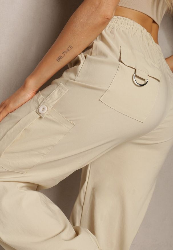 Renee - Jasnobeżowe Szerokie Spodnie High Waist w Stylu Bojówek Wykończone Gumką w Talii Ellcara. Okazja: na co dzień. Stan: podwyższony. Kolor: beżowy. Materiał: satyna. Wzór: moro. Styl: wizytowy, militarny, elegancki, casual, sportowy