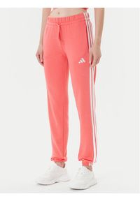 Adidas - adidas Spodnie dresowe Essentials 3-Stripes KE4387 Koralowy Regular Fit. Kolor: pomarańczowy. Materiał: bawełna