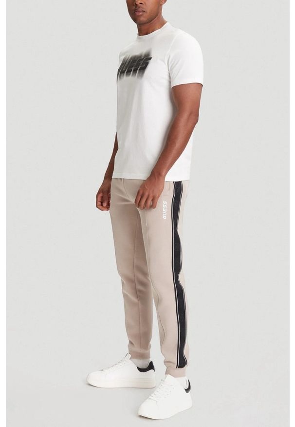 Guess - GUESS Beżowe spodnie męskie z lampasami Mickey, Rozmiar M. Kolor: beżowy