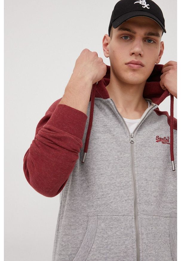 Superdry bluza męska kolor szary z kapturem melanżowa. Okazja: na co dzień. Typ kołnierza: kaptur. Kolor: szary. Materiał: dzianina, bawełna. Długość rękawa: raglanowy rękaw. Wzór: melanż. Styl: casual