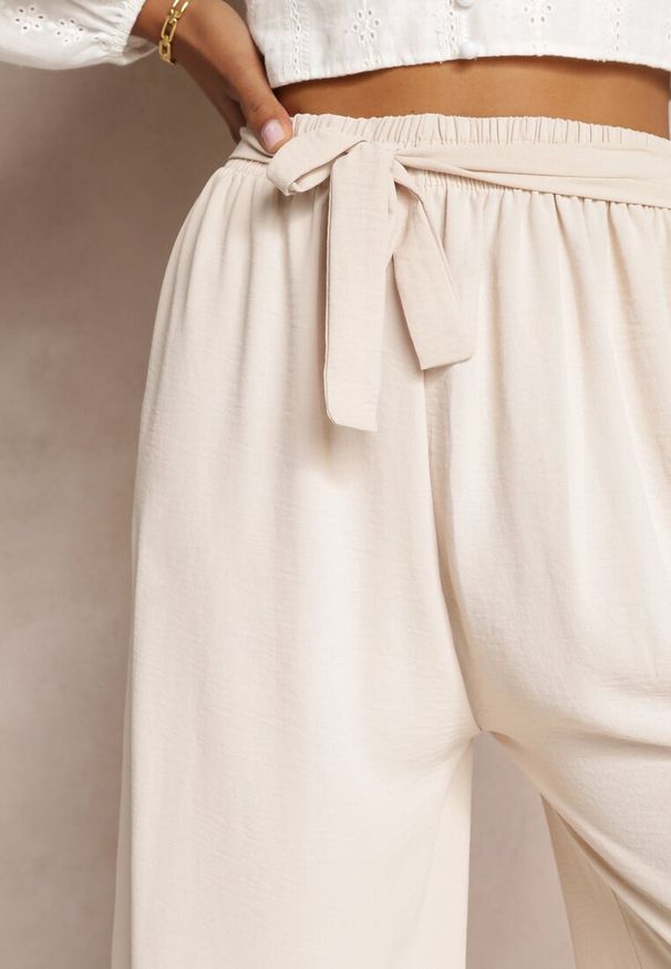 Renee - Jasnobeżowe Spodnie z Szerokimi Nogawkami i Doszytym Paskiem w Talii Atita. Kolor: beżowy