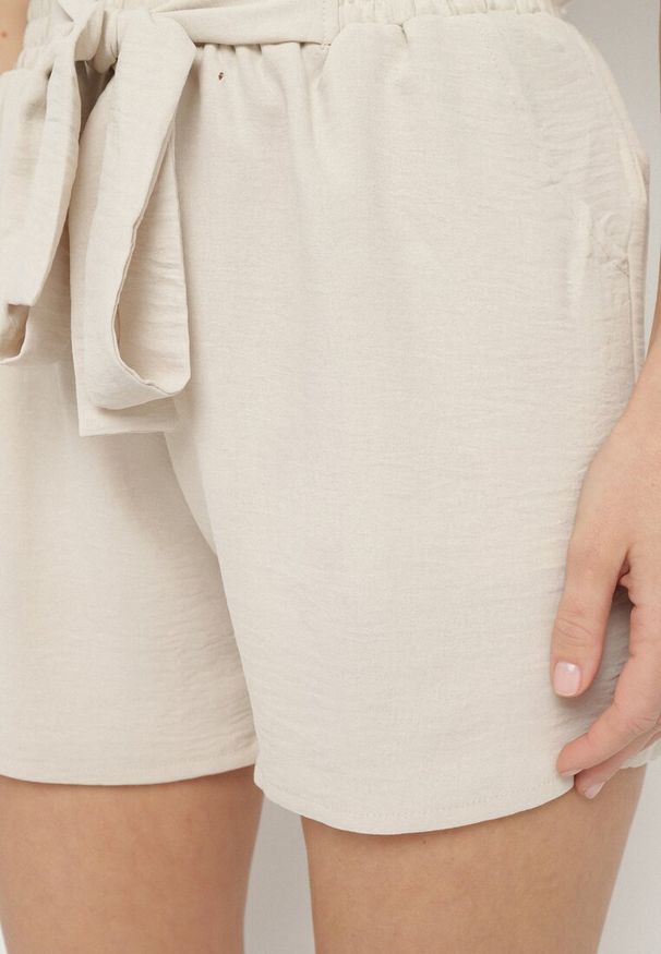 Born2be - Beżowe Szorty z Wysokim Stanem i Gumką w Talii Zdobione Wiązaniem Mevalica. Okazja: na co dzień. Stan: podwyższony. Kolor: beżowy. Długość: krótkie. Wzór: aplikacja. Styl: casual, elegancki