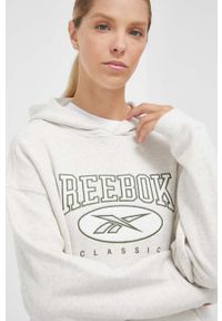 Reebok Classic bluza bawełniana damska kolor beżowy z kapturem z aplikacją. Typ kołnierza: kaptur. Kolor: beżowy. Materiał: bawełna. Długość rękawa: długi rękaw. Długość: długie. Wzór: aplikacja #1