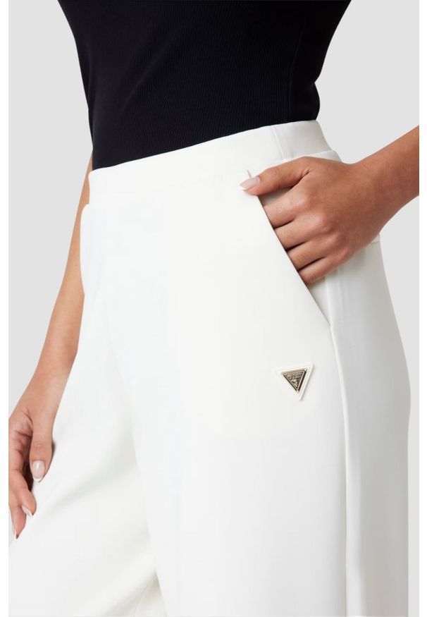 Guess - GUESS Spodnie damskie dresowe ecru Olympe Wide. Kolor: biały. Materiał: dresówka