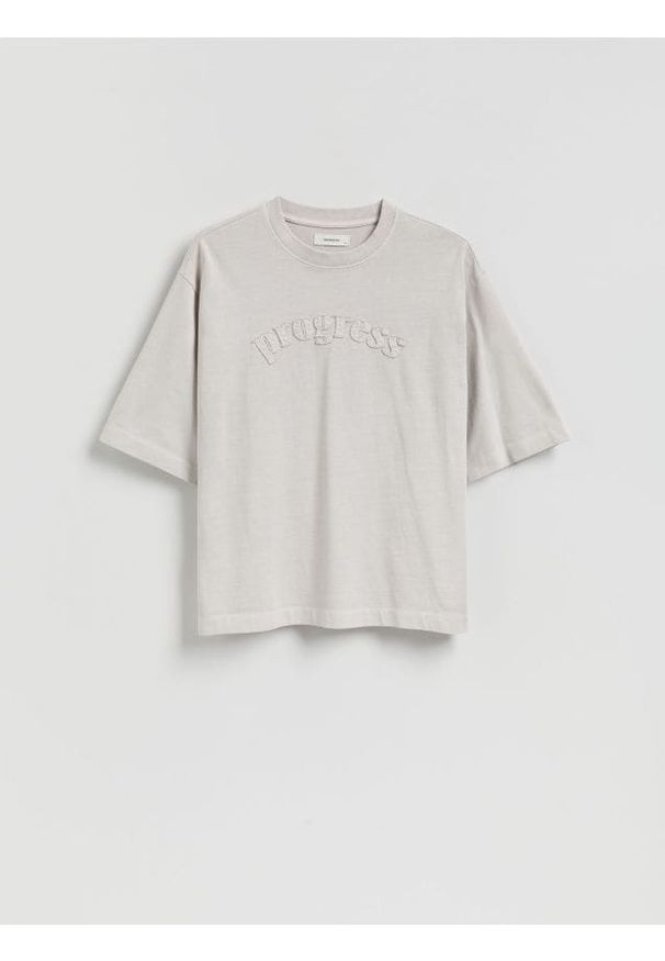 Reserved - T-shirt boxy z naszywką - złamana biel. Materiał: dzianina, bawełna. Wzór: aplikacja