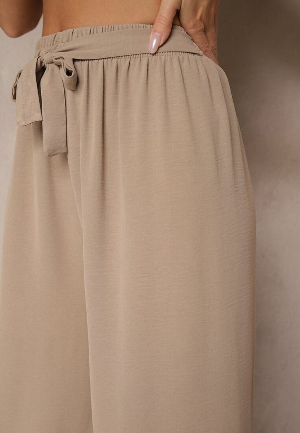 Renee - Ciemnobeżowe Szerokie Spodnie High Waist z Wiązaniem w Talii Reivaritta. Okazja: na co dzień, na spotkanie biznesowe, do pracy. Stan: podwyższony. Kolor: beżowy. Styl: biznesowy, elegancki, casual