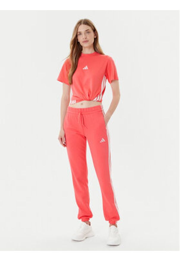 Adidas - adidas Spodnie dresowe Essentials 3-Stripes KE4387 Koralowy Regular Fit. Kolor: pomarańczowy. Materiał: syntetyk, bawełna