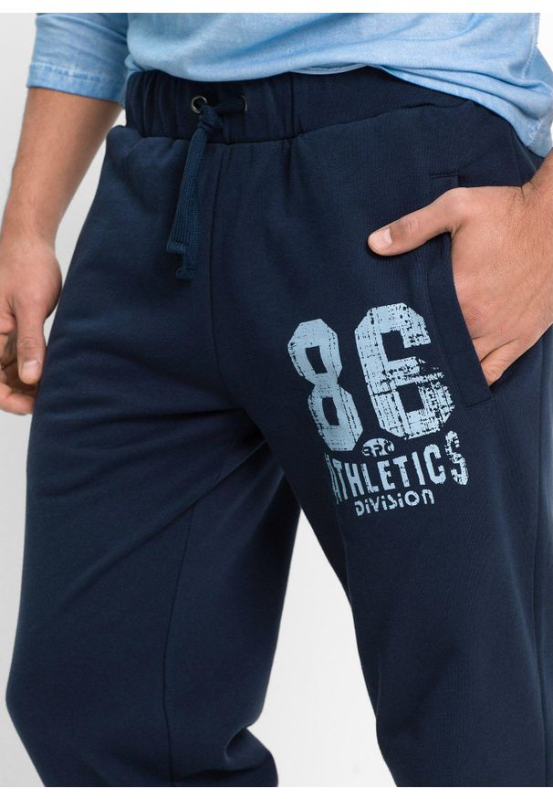 bonprix - Spodnie joggingowe ze sportowymi detalami, z czystej bawełny organicznej. Kolor: niebieski. Materiał: bawełna. Wzór: nadruk. Styl: sportowy