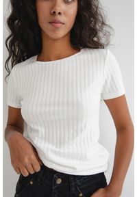 Marsala - Dopasowany top z krótkimi rękawami z delikatnego prążka w kolorze CLASSIC WHITE - UNITY. Kolor: biały. Materiał: materiał, bawełna, prążkowany. Długość rękawa: krótki rękaw. Długość: krótkie. Wzór: prążki