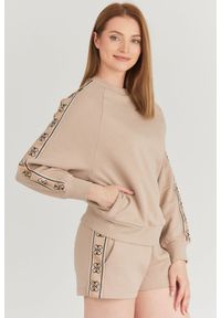 Guess - GUESS Beżowa bluza damska z lampasami w logo. Kolor: beżowy. Materiał: bawełna. Wzór: aplikacja