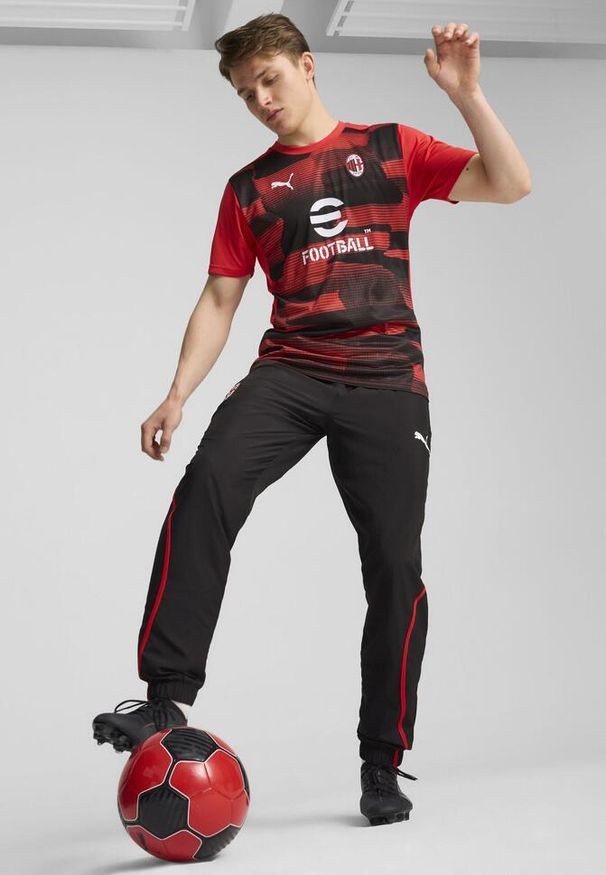 Puma - Męska koszulka przedmeczowa z krótkim rękawem AC Milan PUMA. Kolor: czarny, czerwony, wielokolorowy. Długość rękawa: krótki rękaw. Długość: krótkie