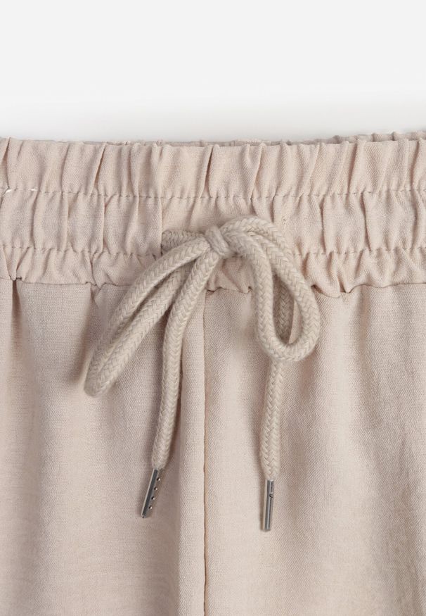Born2be - Beżowe Spodnie Luźne z Kieszeniami i Gumką w Talii oraz Sznurkiem Enivia. Okazja: na co dzień. Kolor: beżowy. Styl: elegancki, casual