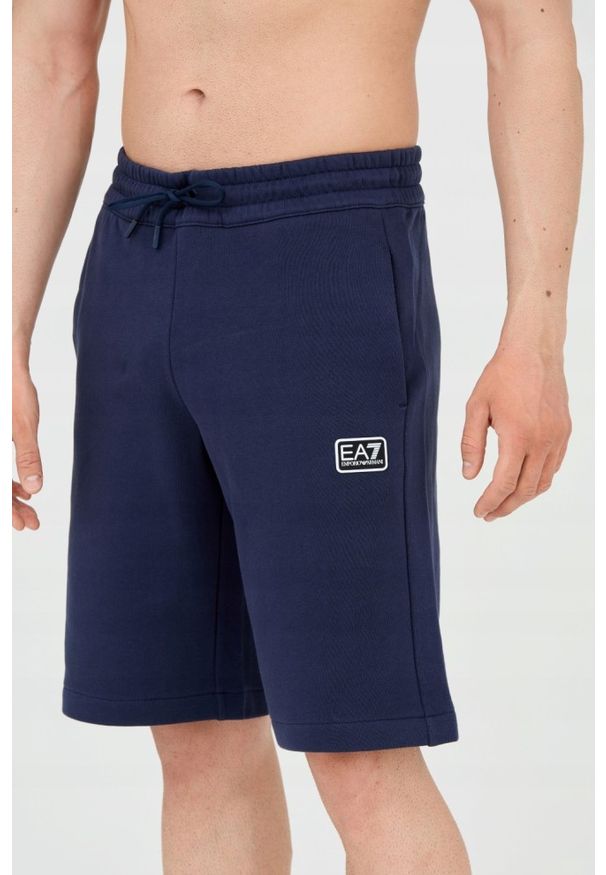 EA7 Emporio Armani - EA7 Męskie granatowe shorty z naszywką. Kolor: niebieski. Materiał: bawełna. Długość: krótkie. Wzór: aplikacja