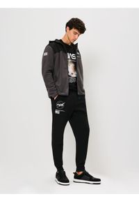 Sinsay - Spodnie tapered fit NASA - czarny. Kolor: czarny