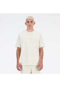 Koszulka męska New Balance MT41559LIN – beżowa. Kolor: beżowy. Materiał: bawełna, dresówka. Długość rękawa: krótki rękaw. Długość: krótkie. Wzór: napisy