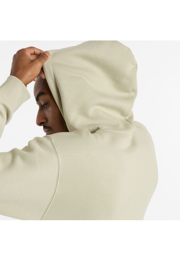 Bluza męska New Balance MT51516OVN – zielona. Typ kołnierza: kaptur. Kolor: zielony. Materiał: poliester, dresówka, materiał, bawełna. Wzór: napisy, aplikacja