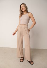 Born2be - Beżowe Spodnie z Wysokim Stanem i Szerokimi Nogawkami Zdobione Guzikiem Kelesh. Okazja: do pracy, na co dzień. Stan: podwyższony. Kolekcja: plus size. Kolor: beżowy. Materiał: tkanina, prążkowany. Długość: długie. Wzór: aplikacja. Styl: elegancki, casual #4