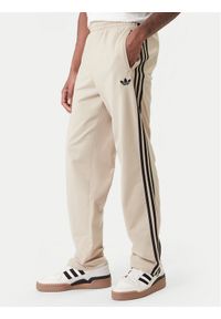 Adidas - adidas Spodnie dresowe Firebird KE6679 Beżowy Loose Fit. Kolor: beżowy. Materiał: syntetyk #1