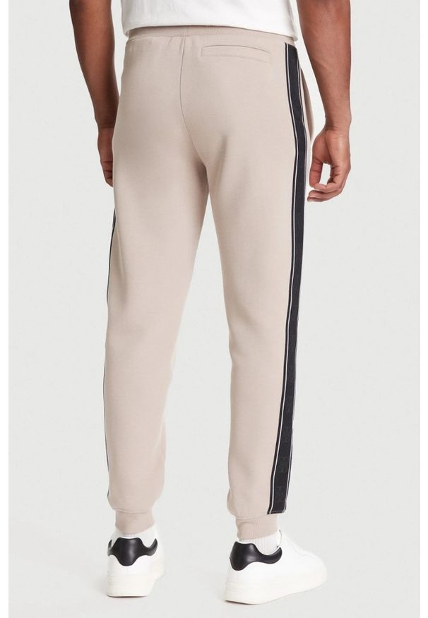 Guess - GUESS Beżowe spodnie męskie z lampasami Mickey, Rozmiar M. Kolor: beżowy