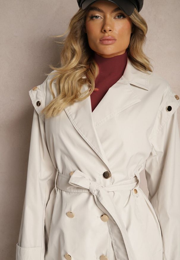 Renee - Jasnobeżowy Płaszcz Trencz o Kroju Oversize Ozdobiony Materiałowym Paskiem i Guzikami Iritheas. Kolor: beżowy. Materiał: materiał. Wzór: aplikacja