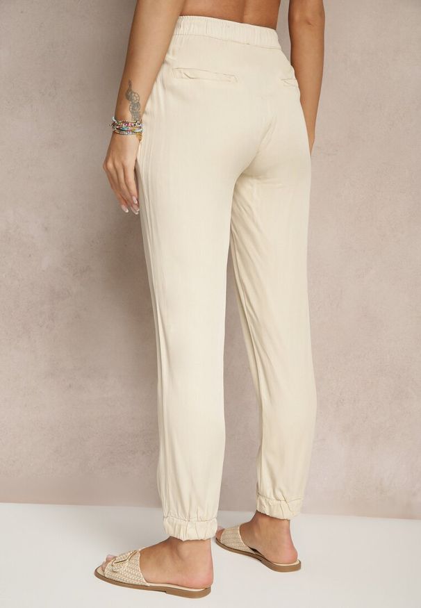 Renee - Jasnobeżowe Spodnie Dresowe High Waist z Ozdobnym Wiązaniem Ellivaria. Okazja: na co dzień. Stan: podwyższony. Kolor: beżowy. Materiał: dresówka. Styl: casual