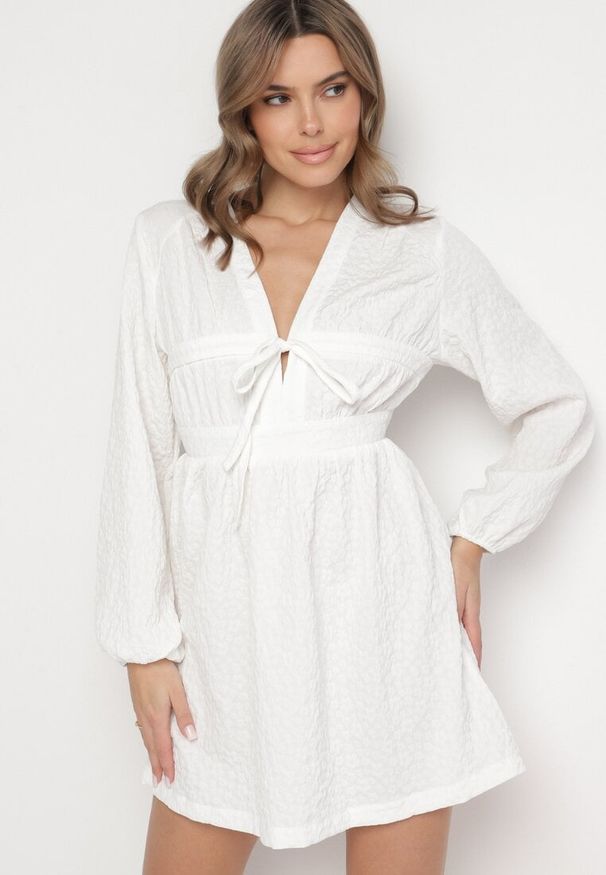 Born2be - Biała Sukienka o Rozkloszowanym Kroju Ozdobiona Wiązaniem Elretira. Okazja: na co dzień. Kolor: biały. Długość rękawa: długi rękaw. Wzór: aplikacja. Typ sukienki: rozkloszowane, proste. Styl: casual, elegancki
