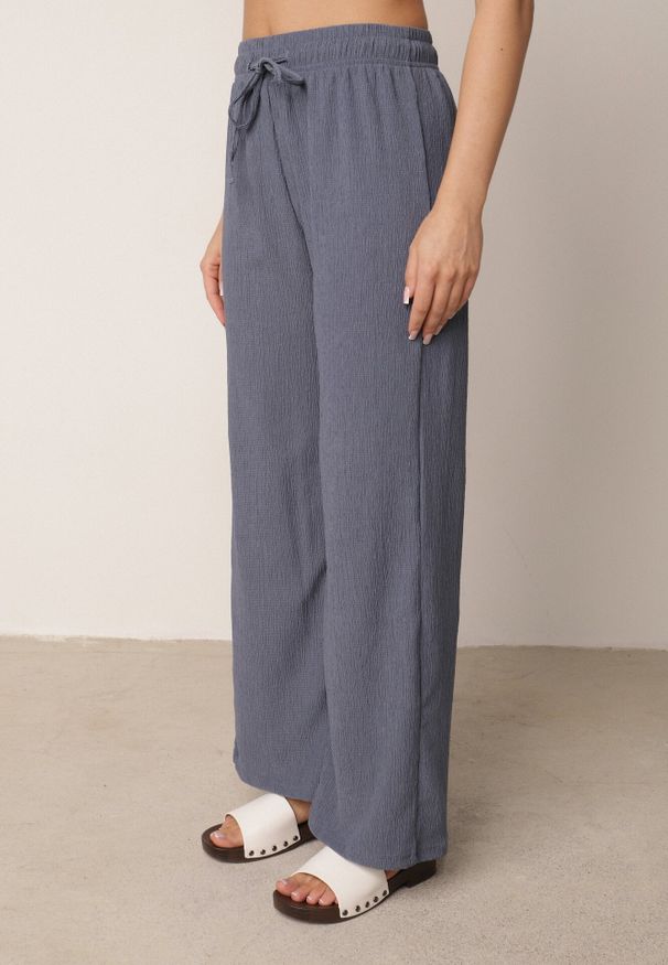 Born2be - Niebieskie Szerokie Spodnie z Teksturalnej Tkaniny z Wiązaniem w Pasie Agatia. Okazja: do pracy, na co dzień, na spacer. Stan: podwyższony. Kolor: niebieski. Materiał: tkanina. Długość: długie. Styl: wakacyjny, casual