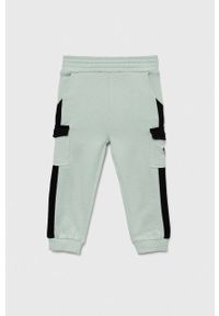 Guess spodnie dresowe bawełniane dziecięce kolor turkusowy wzorzyste. Stan: podwyższony. Kolor: turkusowy. Materiał: bawełna, dresówka