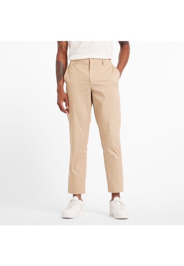 Spodnie męskie New Balance MP43554SOT – beżowe. Kolor: beżowy. Materiał: nylon, materiał, bawełna. Wzór: aplikacja