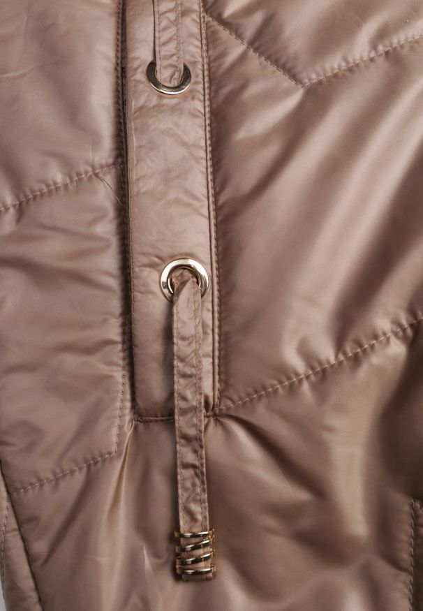 Born2be - Jasnobrązowa Pikowana Kamizelka o Długim Kroju z Nieodpinanym Kapturem i Aplikacją Koretes. Okazja: na co dzień. Kolor: brązowy. Materiał: prążkowany, poliester. Długość: długie. Wzór: aplikacja. Styl: casual