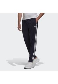 Adidas - Primegreen Essentials Warm-Up Tapered 3-Stripes Track Pants. Kolor: czarny, niebieski, wielokolorowy, biały. Materiał: poliester, dresówka, materiał. Sport: fitness