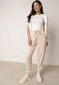 Born2be - Beżowe Spodnie Dresowe Joggery z Wysokim Stanem i Ściągaczami przy Kostkach Janlea. Okazja: do domu, na co dzień, na spacer. Stan: podwyższony. Kolor: beżowy. Materiał: dresówka. Długość: krótkie. Styl: sportowy, klasyczny, casual #4