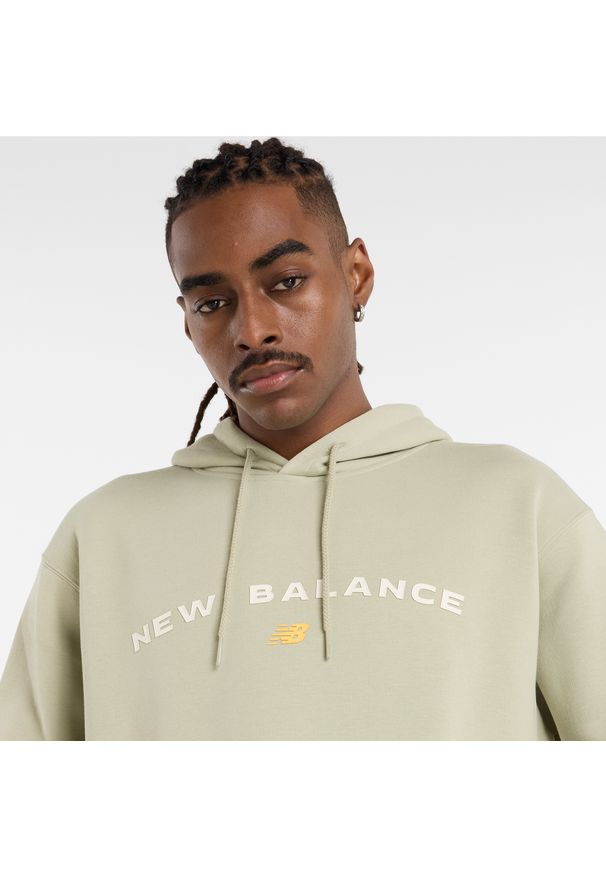 Bluza męska New Balance MT51516OVN – zielona. Typ kołnierza: kaptur. Kolor: zielony. Materiał: poliester, bawełna, dresówka, materiał. Wzór: napisy, aplikacja