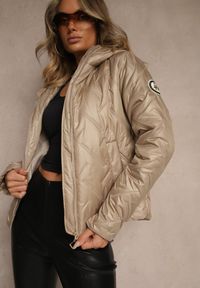 Renee - Jasnobrązowa Kurtka z Kapturem Pikowaniem i Naszywką Rilamea. Okazja: na co dzień, na spacer. Typ kołnierza: kaptur. Kolor: brązowy. Materiał: jeans. Wzór: aplikacja. Styl: sportowy, casual, elegancki