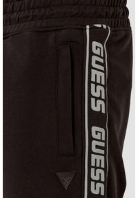 Guess - GUESS Brązowe męskie spodnie dresowe z lampasami New Arlo. Kolor: brązowy. Materiał: dresówka #5