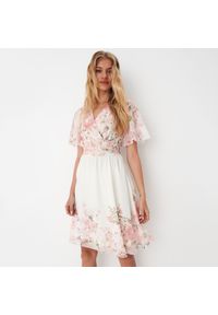 Mohito - Kopertowa sukienka mini w kwiaty - Kremowy. Kolor: kremowy. Wzór: kwiaty. Typ sukienki: kopertowe. Długość: mini
