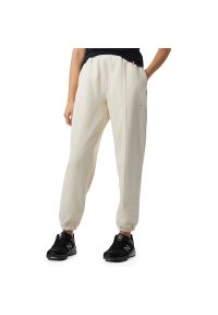 Spodnie New Balance WP23553GIE - beżowe. Kolor: beżowy. Materiał: poliester, materiał, dresówka, bawełna. Wzór: napisy