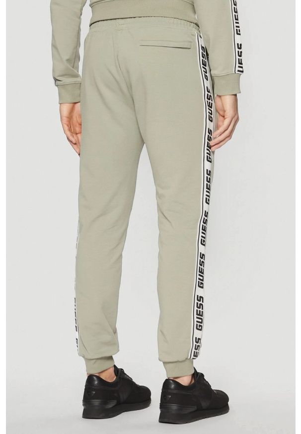 Guess - GUESS Zielone męskie spodnie dresowe z lampasami New Arlo, Rozmiar XL. Kolor: zielony. Materiał: dresówka