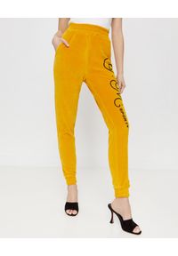 JOANNA MUZYK - Aksamitne spodnie z logo. Stan: podwyższony. Kolor: żółty. Materiał: dresówka. Wzór: aplikacja